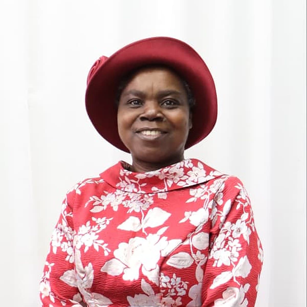 Deaconess Grace Adusi in a red hat and a red floral dress