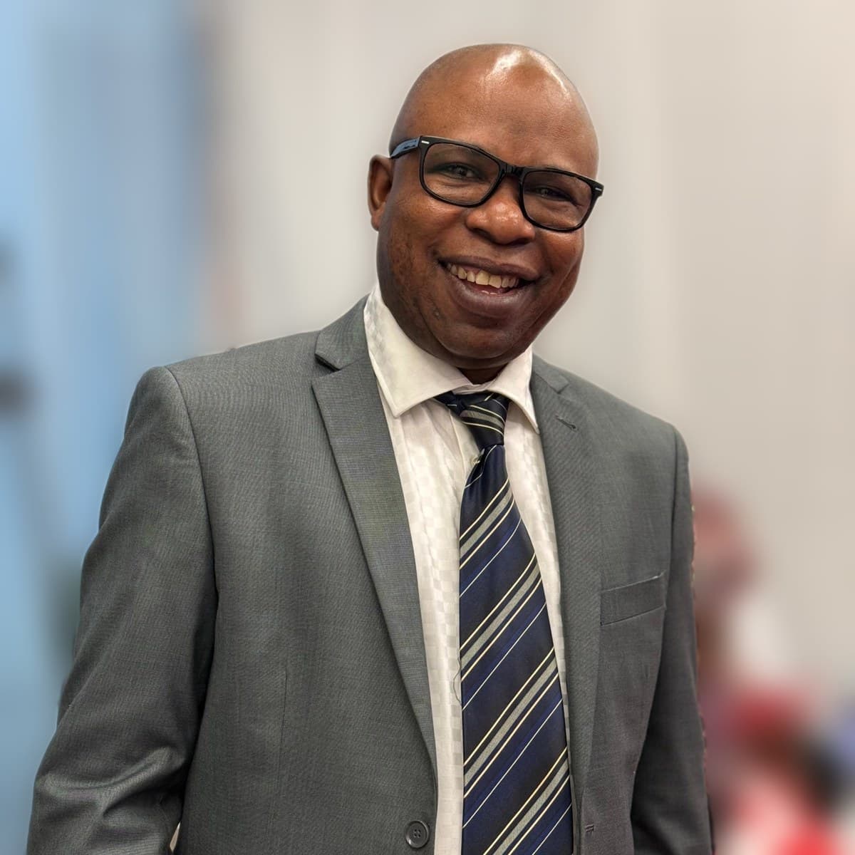 Pastor Jeff Ogboe in a grey suit and a striped tie
