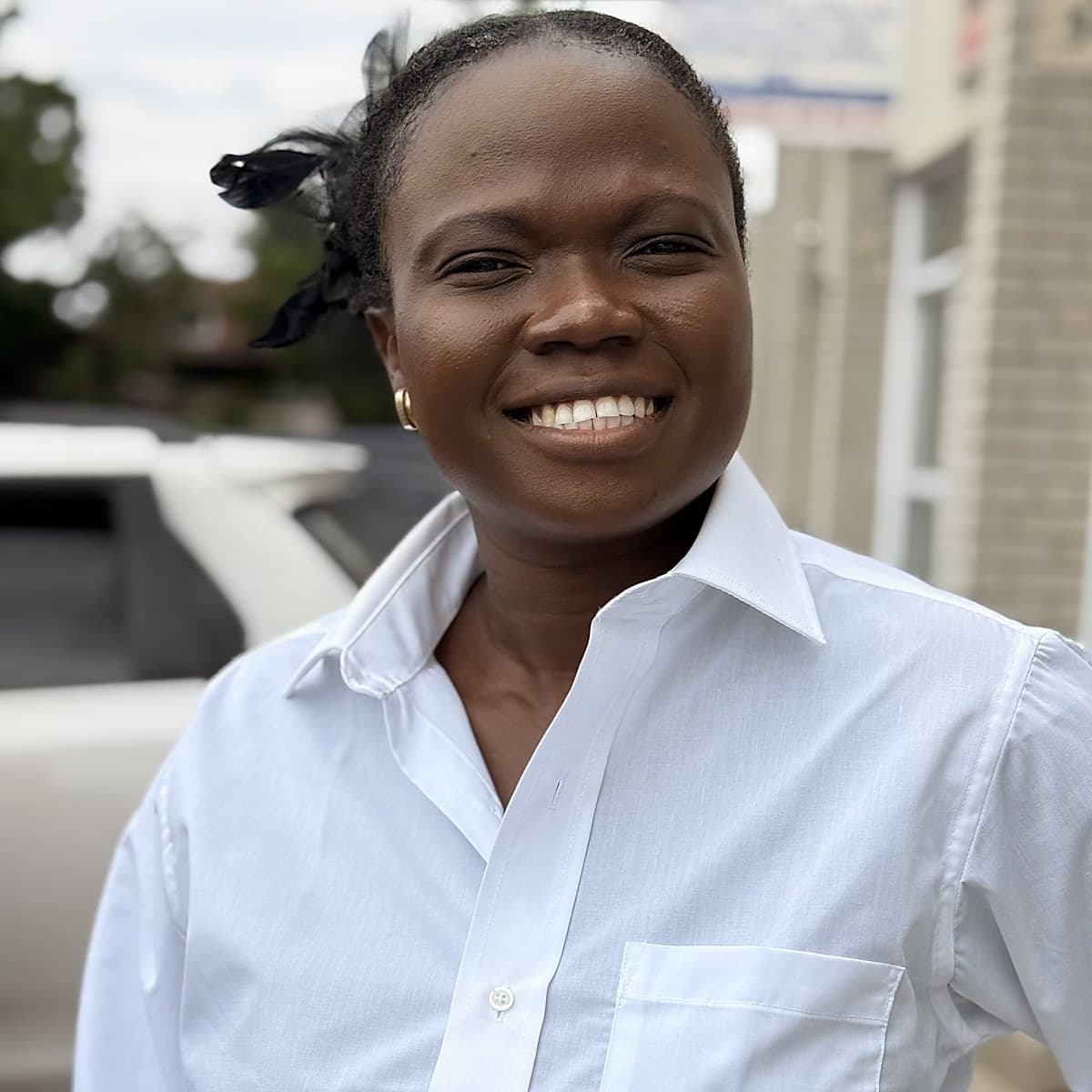 Sister Ebunoluwa in a white shirt, outdoors on a bright day